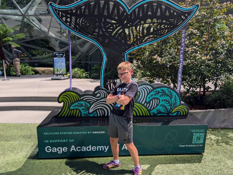 Theo Hodo at Amazon Kids Day posing with one of the Seattle World Cup signs